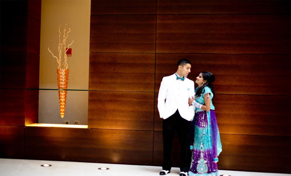 Couple in formal attire beside a modern wall