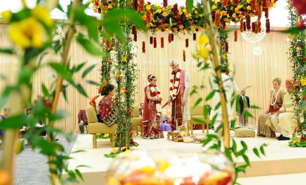Bride and groom standing beneath a floral ceremony canopy